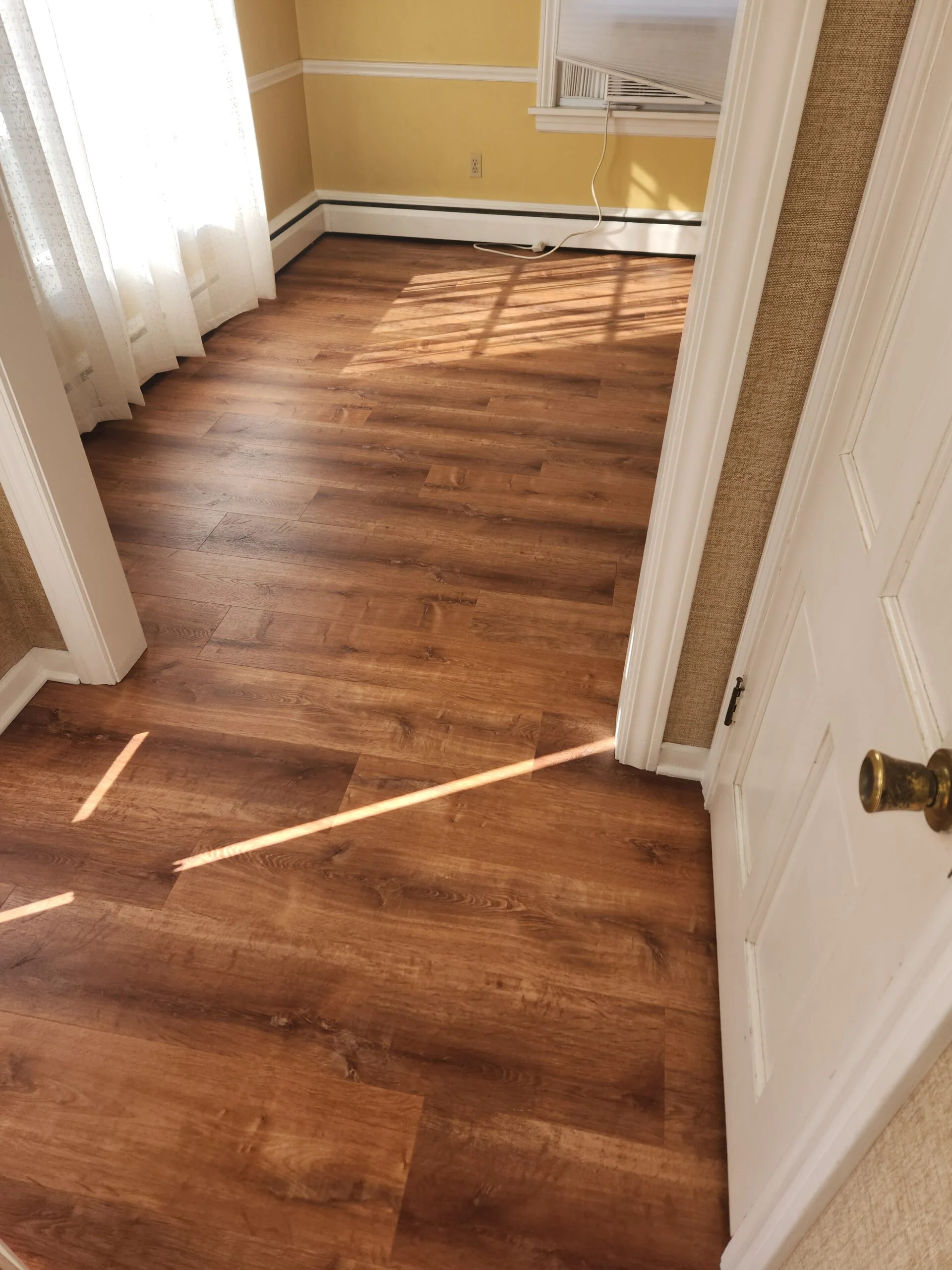 Close-up of flawlessly installed luxury vinyl plank flooring in a modern residential living room.