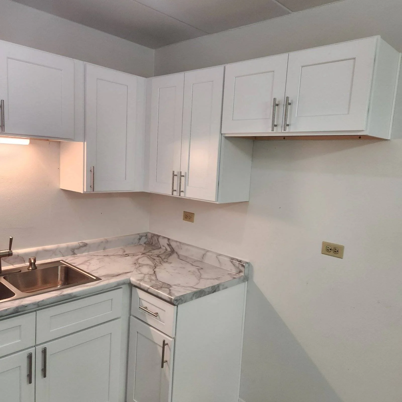 Modern white kitchen cabinets with marble countertops and stainless steel sink after kitchen remodeling